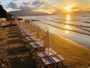 una línea de sillas de playa con sombrillas en una playa en Appartamento a pochi metri dal mare La Giara, en Balestrate