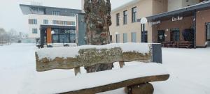a bench covered in snow in front of a building at Hotel Viktorosa in Hofgeismar