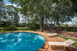 a swimming pool with two lawn chairs and a swing at Carlton Suítes Limeira in Limeira