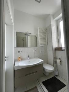 a white bathroom with a sink and a toilet at Joanna Apartment - MA Rheinau in Mannheim