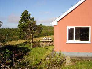 a red building with a picnic table in a field at 2 bedrooms house with garden at Laghy in Laghy