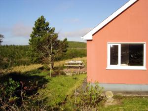 un edificio rojo con una mesa de picnic en un campo en 2 bedrooms house with garden at Laghy, en Laghy