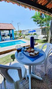 a table with a plate of food on it next to a pool at Pousada da Praia in Itaipuaçu