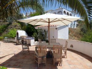 a table and chairs with an umbrella on a patio at Villa Perla Blanca in Sayalonga