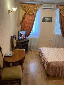 a room with a bed and a table and a television at Отель Ритм in Vinnytsya
