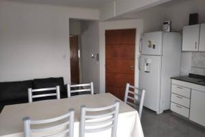 a kitchen with a table and chairs and a white refrigerator at Colòn Termas y Playa - Departamento 2 a 4 personas in Colón