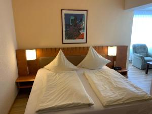 um quarto com uma cama com lençóis brancos e almofadas em Hotel Martina em Bad Sooden-Allendorf