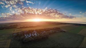 een luchtfoto van een huis met de zonsondergang op de achtergrond bij DOMO CAMP Sylt - Glamping Camp in Westerwall