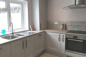 a kitchen with white cabinets and a sink and a window at BROOK COTTAGE in Whitstable