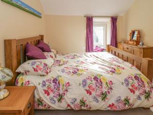 1 dormitorio con 1 cama con colcha de flores en 1 Rhys Terrace, en Pennal