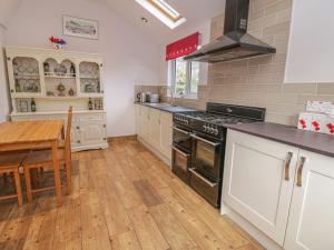 a kitchen with a stove and a table in it at 1 Rhys Terrace in Pennal