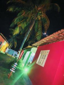 un edificio rosa con una palmera delante en Condomínio Village do Itanhém, en Alcobaça