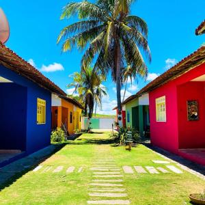 una fila de casas coloridas con una palmera en Condomínio Village do Itanhém, en Alcobaça