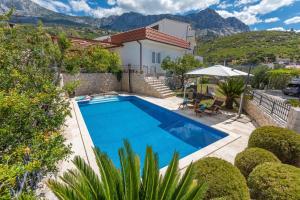 a swimming pool in front of a house with mountains at Villa OLD OLIVE, 3lovelyvillas in Podgora
