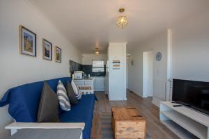 salon z niebieską kanapą i telewizorem w obiekcie Blouberg Beachfront Apartment - Loadshedding free w mieście Bloubergstrand
