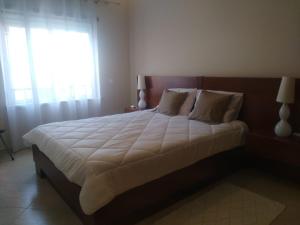 a bedroom with a large white bed with a window at Almancil Park Apartment in Almancil