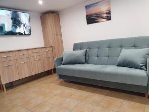 a living room with a couch and a tv at Kwatery u Beaty in Krynica Morska - Piaski