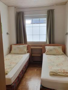 dwa łóżka w małym pokoju z oknem w obiekcie Eden´s Ferienwohnungen w mieście Neuharlingersiel