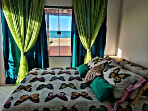 a bed with a comforter with butterflies on it at Pousada Dalva in Galinhos