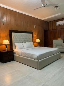 a bedroom with a large bed with two lamps and a chair at Royal Motel Executive in Islamabad