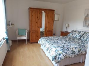 a bedroom with a bed and a cabinet and a chair at Lurig View B&B in Cushendall