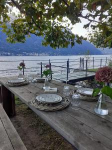 内索Le Vetrate sul Lago Lake Como Amazing View的一张木桌,上面有盘子和盘子,在水边