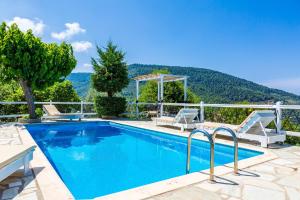 una piscina con dos sillas y una mesa en Villa Glysteri, en Skopelos Town