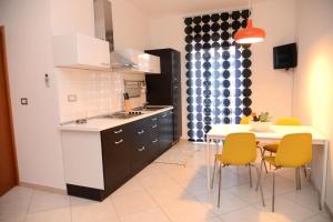 a kitchen with a table and yellow chairs and a table and a kitchen with at Jonico Guest House in Scanzano