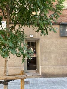 un edificio con una puerta y un árbol delante de él en GranVia Fira Apartment, en Hospitalet de Llobregat