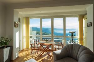 ein Wohnzimmer mit einem Tisch und Stühlen sowie einem großen Fenster in der Unterkunft Tsarevets panoramic apartments Veliko Tarnovo in Weliko Tarnowo