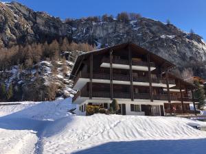 un grande edificio nella neve di fronte a una montagna di L'Hérensarde, bel appartement avec jardin-terrasse et garage a Evolène