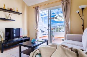 a living room with a couch and a tv and a balcony at Cactus in Puerto del Carmen