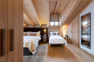 two beds in a room with wooden ceilings at Hôtel de Verbier SUP in Verbier +33 photos