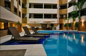 a swimming pool with lounge chairs and a building at Gold Flat Cabo Branco in João Pessoa
