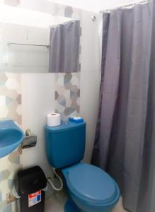 a bathroom with a blue toilet and a sink at Vista Palmeras in Zorritos