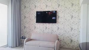 a living room with a chair and a television on a wall at Studio Jebel Sifah Resort Golf Lake G 14 - 201 in As Sīfah
