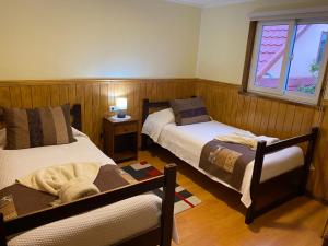 a bedroom with two beds and a window at Hostal America en Puerto Natales in Puerto Natales