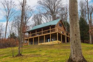 a large wooden house with a green roof at Pine Creek HC Hocking Hills Cabins in South Bloomingville