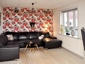 een woonkamer met een zwarte leren bank en een bloemenmuur bij Holiday home Thyborøn IV in Thyborøn