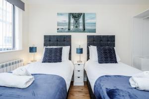 2 łóżka w sypialni w kolorze niebieskim i białym w obiekcie Queens Serviced Apartments - F1 w mieście Watford