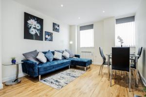 a living room with a blue couch and a table at Queens Serviced Apartments - F1 in Watford