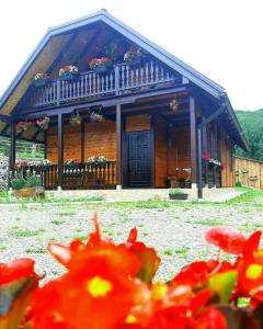 une maison en bois avec des fleurs devant elle dans l'établissement Brvnara Sofiana, à Bajina Bašta