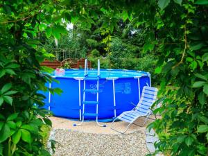 a blue pool with two chairs next to it at Lovely Apartment in Rusko with Pool Garden in Darłowo