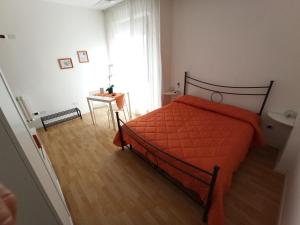 a bedroom with a bed with an orange comforter at Like Home Cisanello in Pisa