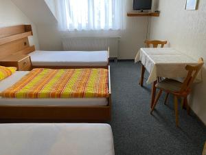a room with two beds and a table and a table and chair at Grüne Au Hotel in Hasselroth