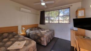 a room with two beds and a flat screen tv at Gunnedah Motor Inn in Gunnedah