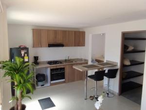 a kitchen with wooden cabinets and a island with bar stools at 6 Apartaestudio independiente, Cedritos in Bogotá