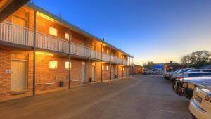 a building with cars parked in a parking lot at Gunnedah Motor Inn in Gunnedah