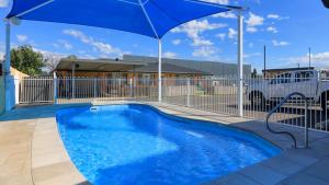 una piscina azul con sombrilla azul en Gunnedah Motor Inn, en Gunnedah