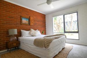a bedroom with a bed and a brick wall at Solace Retreat in Rye
